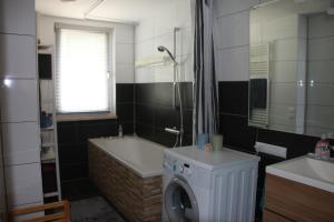 a bathroom with a washing machine and a bath tub at Ferienhaus am Ellerbach in Bad Dürrenberg