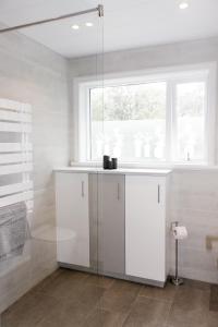 a white bathroom with a sink and a window at Siddy Apartment in Reykjavík