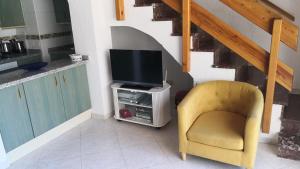 un salon avec une chaise jaune et une télévision dans l'établissement Skol 408A by Completely Marbella, à Marbella