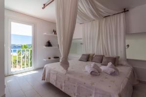a bedroom with a bed with a canopy and a window at Villa Arola in Cala Comte