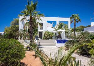 Casa blanca con palmeras y piscina en Villa Arola, en Cala Comte
