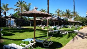 un groupe de chaises et de parasols sur l'herbe dans l'établissement Skol 408A by Completely Marbella, à Marbella