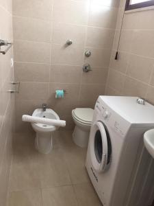 a bathroom with a toilet and a washing machine in it at Solemare Beach Apartment Trapani in Erice