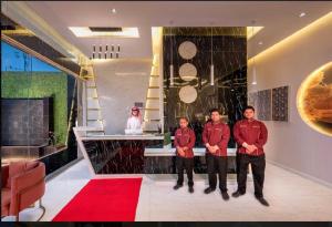 tres hombres parados en una habitación con una alfombra roja en الحياة إن للأجنحة الفندقيه, en Abha