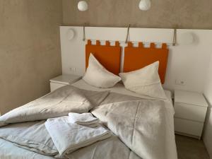ein Bett mit weißer Bettwäsche und Kissen darauf in der Unterkunft Rennweg 114 in Meran