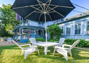 una mesa, sillas y una sombrilla frente a una casa en Narragansett House, en Oak Bluffs