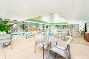 ein Zimmer mit Tischen und Stühlen sowie einem Pool in der Unterkunft Holiday Inn Express - Delafield, an IHG Hotel in Delafield