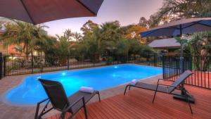 a swimming pool with two chairs and an umbrella at Heritage River Motor Inn in Grafton
