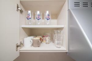 a cupboard filled with lots of glasses and mugs at Hokusai Stay in Osaka