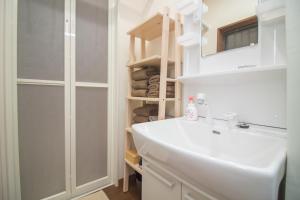 a white bathroom with a sink and a mirror at Hokusai Stay in Osaka