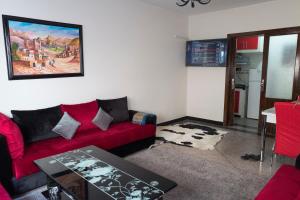 Modern and Cozy Apartment في الدار البيضاء: غرفة معيشة مع أريكة حمراء وطاولة