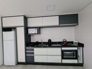 a kitchen with black and white cabinets and a refrigerator at Apartamento Familiar II - Vista para o mar e próximo ao Beto Carrero in Penha