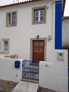 a white house with a blue gate and a door at Casa Mateus - Colares, Parque Natural Sintra Cascais in Sintra