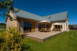 a building with a deck with tables and umbrellas at Clovenstone Lodges in Inverurie