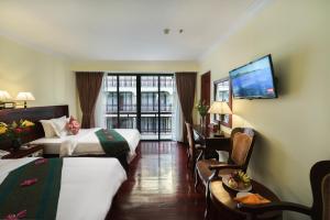 a hotel room with two beds and a flat screen tv at Smiling Deluxe Hotel in Siem Reap