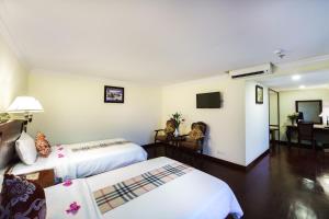 a hotel room with two beds and a television at Smiling Deluxe Hotel in Siem Reap