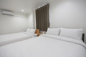 two beds in a room with white sheets at INTERest POSHTEL in Bangkok