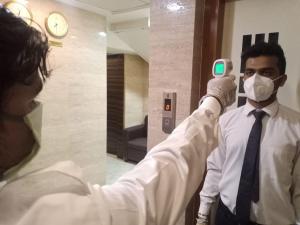 uma pessoa a tirar uma fotografia a um homem com uma máscara em Hotel Alfa International em Mumbai