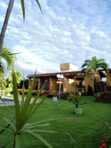 a house with a green yard with a palm tree at Pousada Aconchego in Pitimbu