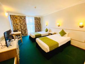 um quarto de hotel com duas camas e uma televisão de ecrã plano em Acacia Court Hotel em Cairns