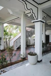 un gran patio con columnas blancas y una maceta. en Sunset View Beach Hotel, en Arugam Bay