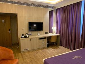 a hotel room with a desk and a flat screen tv at Midtown Grand in Hisār