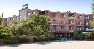 duży ceglany budynek z drzewami przed nim w obiekcie Hotel Grillo w mieście Assemini