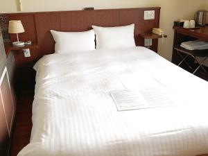 a bed with white sheets and pillows in a room at Sutton Hotel Hakata City in Fukuoka