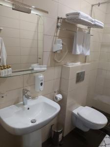 Baño blanco con lavabo y aseo en DK Kompleks Hotel, en Novosibirsk