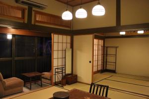 Historical Ryokan SENYUKAN في Ōwani: غرفة معيشة مع طاولة وكراسي وأضواء
