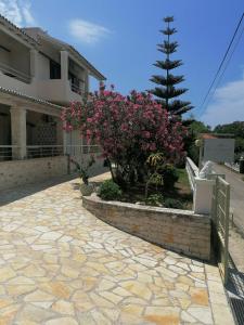 a house with a brick walkway and pink flowers at Makis Apartments in Arillas