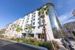 a building with a palm tree in front of it at Goldstar Resort & Suites in Nice