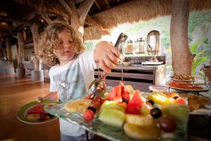 a young child is reaching for a tray of fruit at Novotel Lombok Resort & Villas in Kuta Lombok