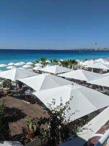 una playa con sombrillas blancas y el océano en Goldstar Apartments & Suites, en Niza