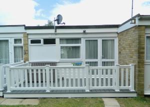 a white fence in front of a house at Bespoke Chalet 214, walk to the beach & close to Norfolk broads - pet friendly! in Great Yarmouth