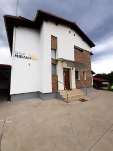 un bâtiment blanc avec un panneau sur son côté dans l'établissement MIRANA, à Cristian
