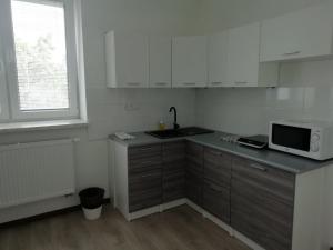 a kitchen with white cabinets and a sink and a microwave at Apartmány Stdaniela in Bohumín