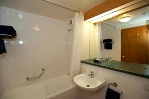 a bathroom with a tub and a sink and a mirror at Swiss-Belresort Coronet Peak in Queenstown