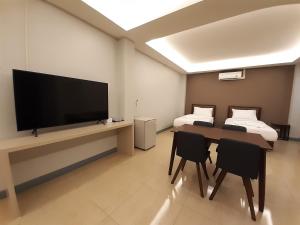 uma sala de estar com uma televisão e uma mesa e cadeiras em Zleep D Hotel em Udon Thani