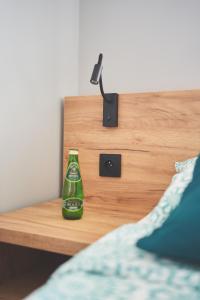 a bottle on a night stand next to a bed at Apartamenty SZAROTKA Nowy Targ in Nowy Targ