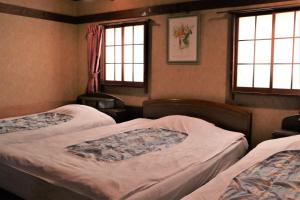 two beds in a room with two windows at Hotel Daiki in Osaka