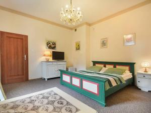 Un dormitorio con una cama, un televisor y una lámpara de araña. en Apartamenty Słupskie, en Słupsk