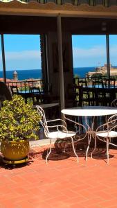 eine Terrasse mit einem Tisch, Stühlen und Meerblick in der Unterkunft HOTEL AMBEILLE in Collioure