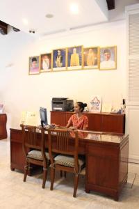 une femme assise sur un bureau avec un ordinateur dans l'établissement Heeren Straits Hotel, à Malacca