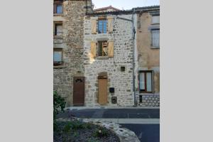 a stone house with a door and a building at Maison de bourg in Vic-le-Comte
