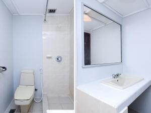 La salle de bains blanche est pourvue d'un lavabo et d'un miroir. dans l'établissement Super OYO 1018 Telang Usan Hotel Miri, à Miri