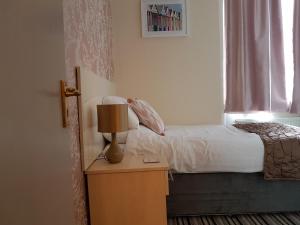 a bedroom with a bed and a lamp on a table at 74 Belgravia in Torquay