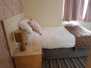 a bedroom with a bed and a table with a lamp at 74 Belgravia in Torquay