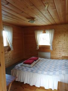 a bed in a wooden room with two windows at Hannuksen Piilopirtti in Tyrnävä
