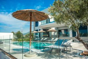 a pool with umbrellas and chairs next to a house at Premium Ionian Villas - Vlachata in Vlachata